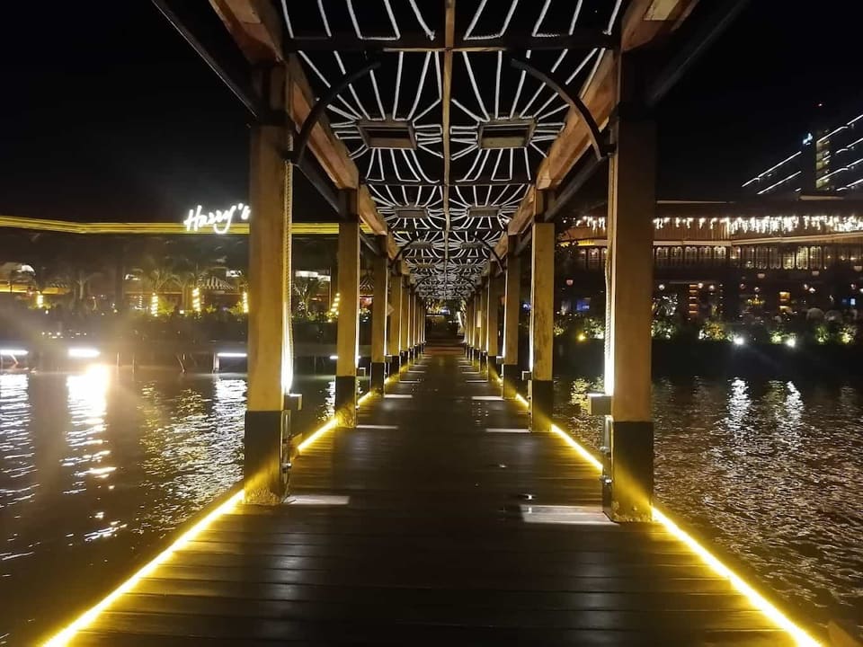 Pasarela comercial con pórticos de madera, celosías tejidas e iluminación lineal cálida